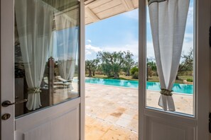 A door leading to a pool area with a view of the pool and surrounding greenery. - Villa Antica Dimora by MMega (Castellana Grotte)