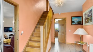 A staircase leading to a second floor, a television in the living area, and a painting on the wall.