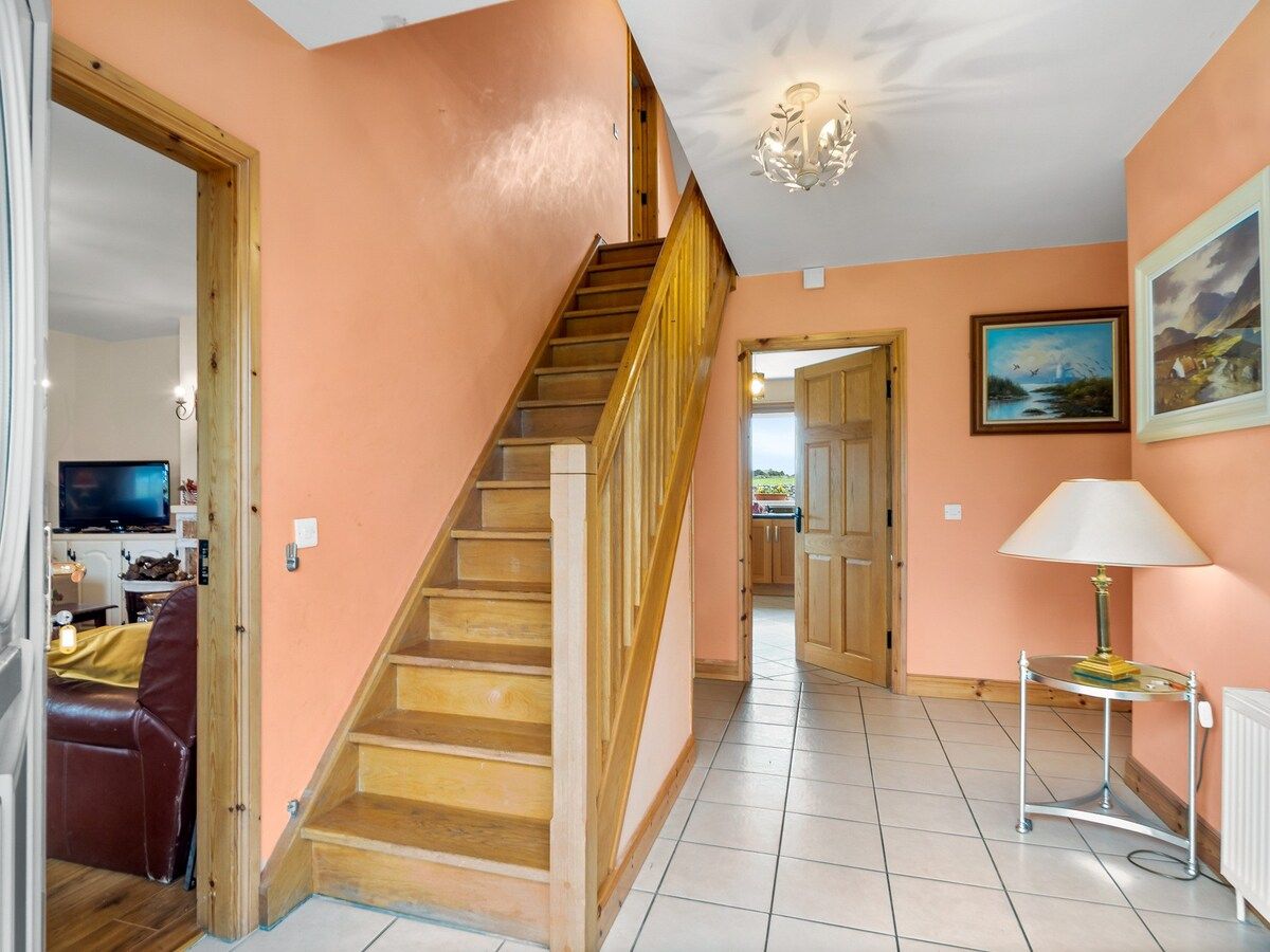 A staircase leading to a second floor, a living area with a sofa and TV, and a dining area with a table and chairs.