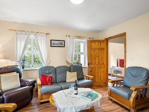A living room with a sofa, armchairs, a coffee table, and a wooden door.