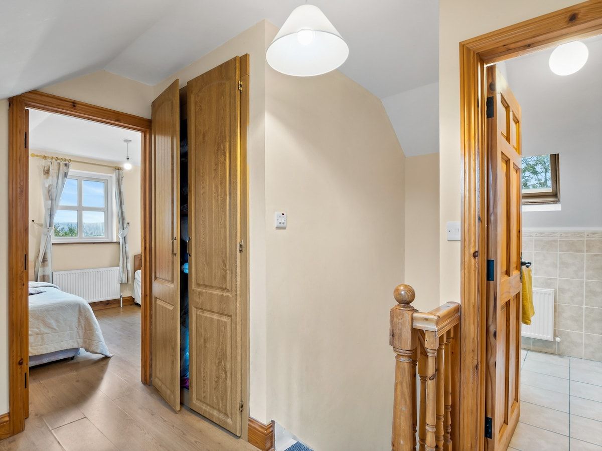 Een kamer met een bed, een houten deur en een lamp.