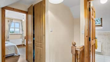 Een kamer met een bed, een houten deur en een lamp.