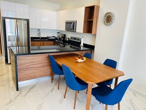Una cocina moderna con armarios blancos, un refrigerador de acero inoxidable, un microondas y un horno empotrado.