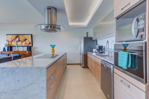 A modern kitchen with a central island, stainless steel appliances, and a dining area with a wooden table and chairs.