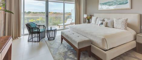 A spacious bedroom with a large bed, a ceiling fan, and a balcony with a chair.