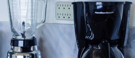 A kitchen with a blender and a coffee maker on the counter.