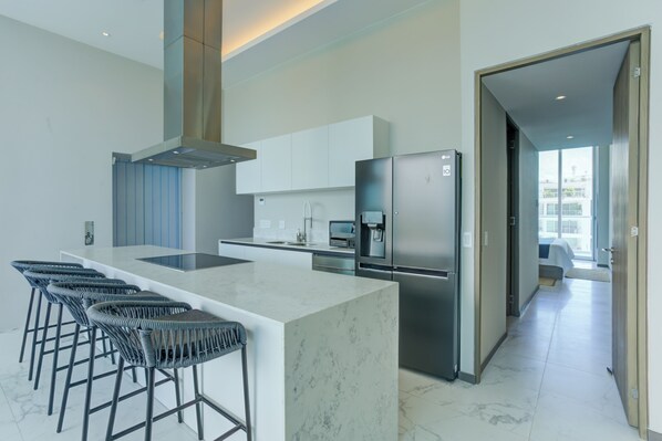A modern kitchen with a marble island, stainless steel appliances, and bar stools.