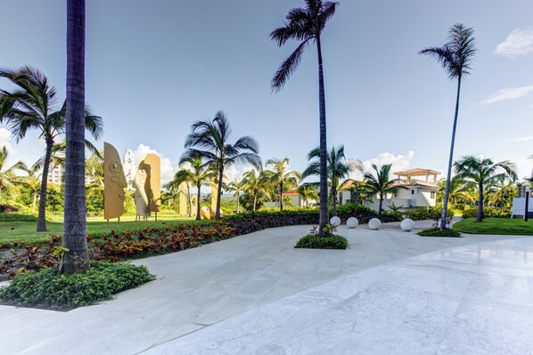 A resort with palm trees, a paved walkway, and a building with a red roof. - Marítima Beachfront Playa Flamingos (Nuevo Nayarit)