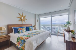 A modern bedroom with a large bed, a city view, and a sun-shaped wall decoration. - Marítima Beachfront Playa Flamingos (Nuevo Nayarit)