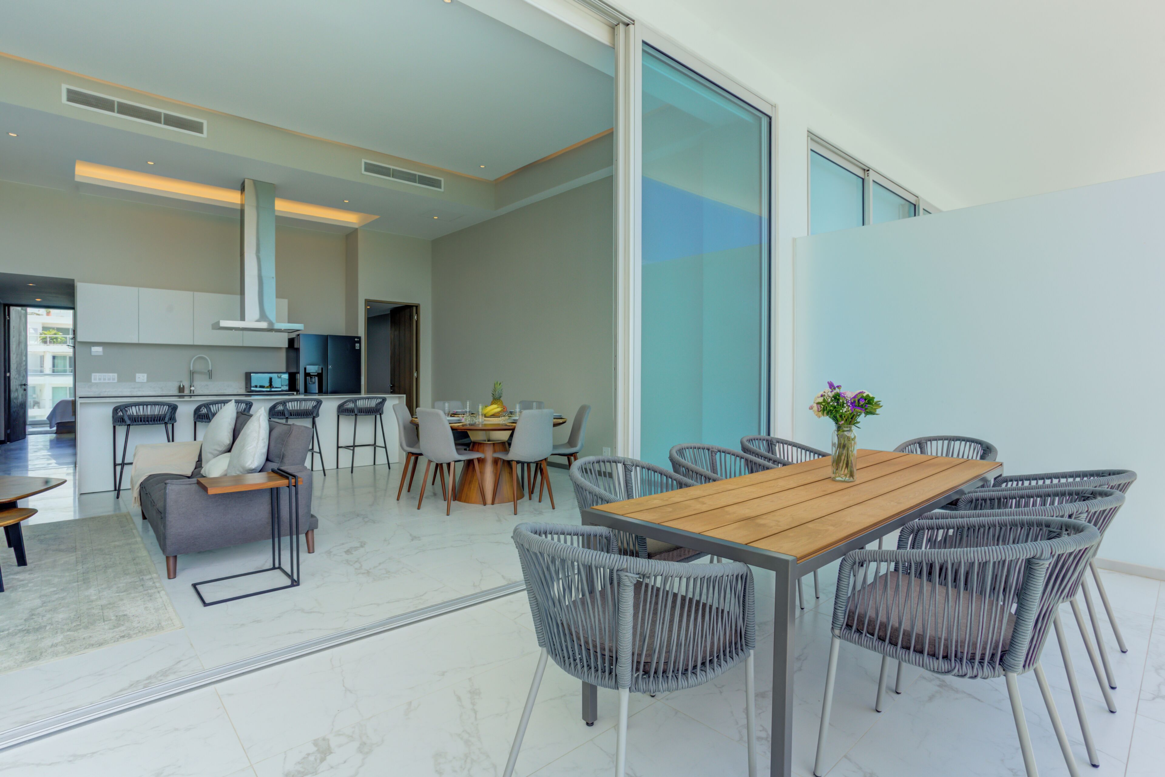 Een moderne keuken met witte kasten, een centraal eiland en barstoelen.
