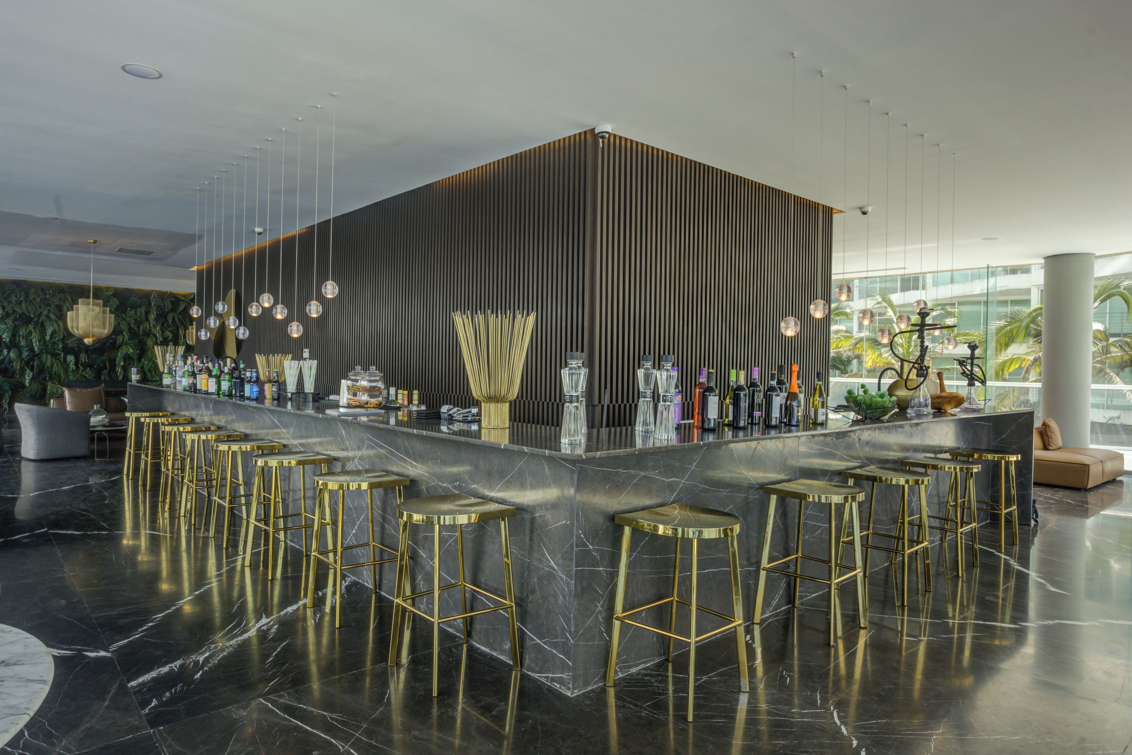 A modern bar area with a central island, bar stools, and a variety of bottles and glasses.