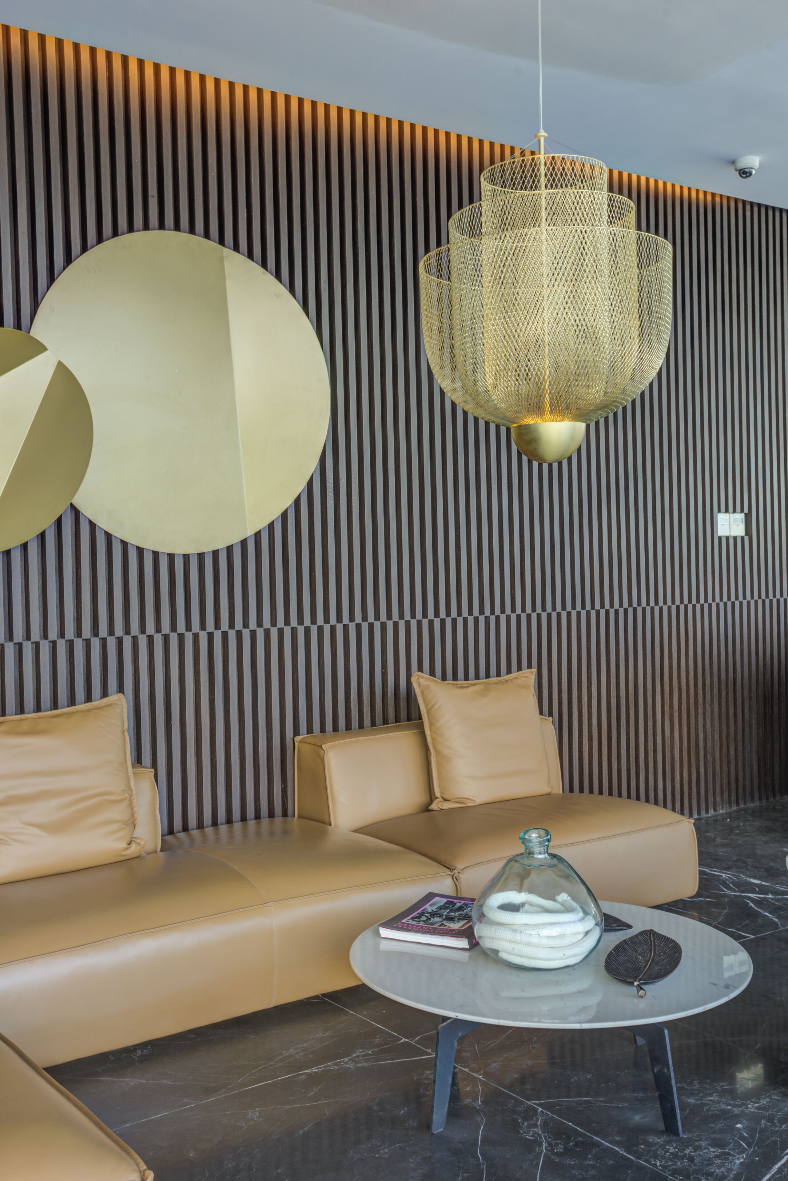 A modern interior with a leather sofa, a round glass table, and a unique hanging light fixture.