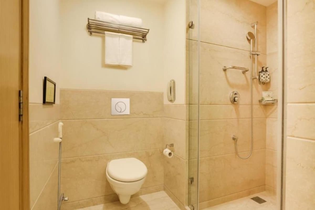 A small, modern bathroom with a toilet, a glass shower enclosure, and a towel rack.
