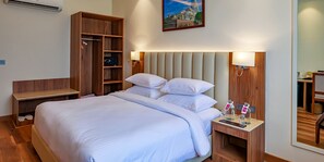 A hotel room with a large bed, wooden wardrobe, bedside tables with lamps, and a mirror. - Hotel Luxe Stay (New Delhi)