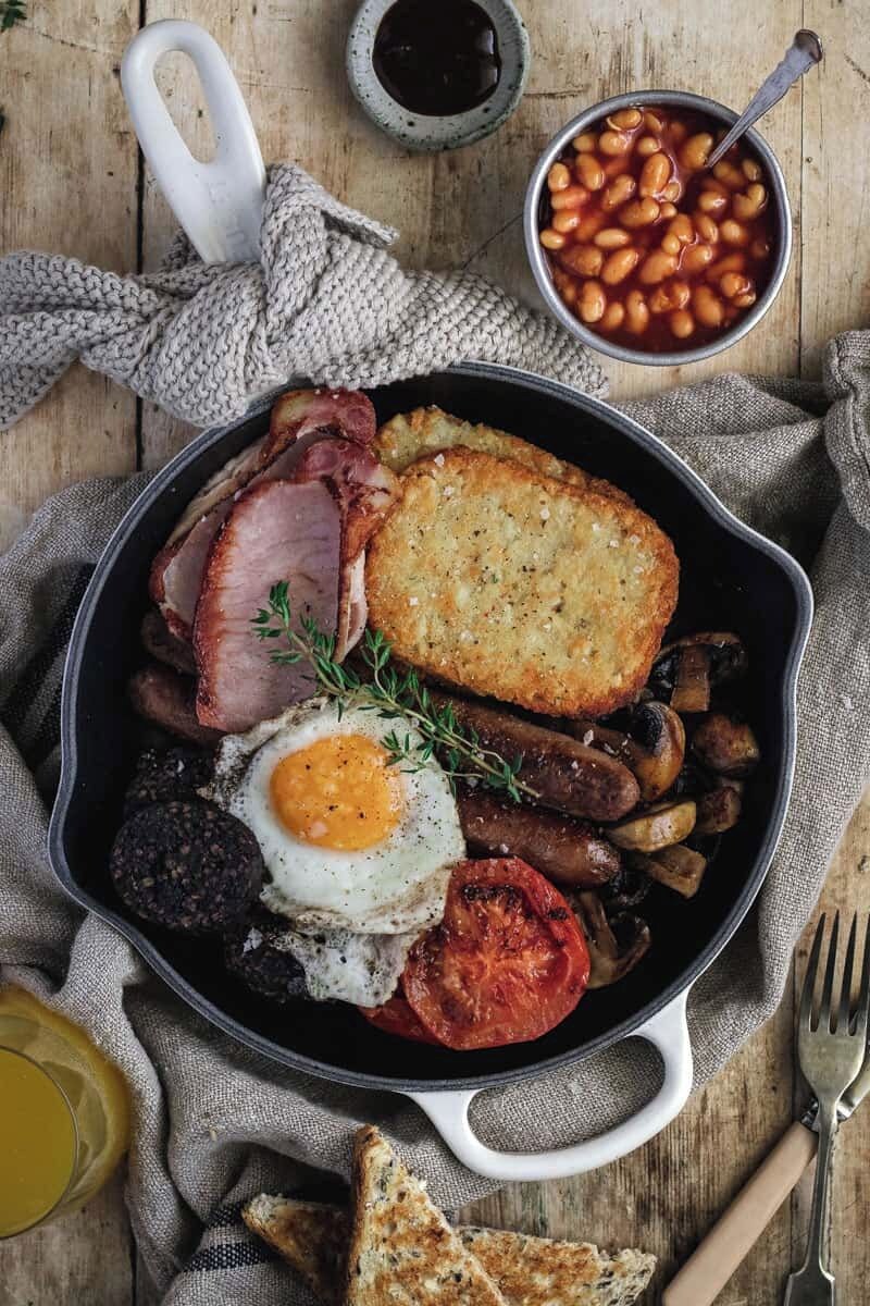 A skillet with a variety of breakfast items including eggs, bacon, mushrooms, and toast.