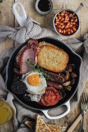 A skillet with a variety of breakfast items including eggs, bacon, mushrooms, and toast. - Hotel Luxe Stay (New Delhi)