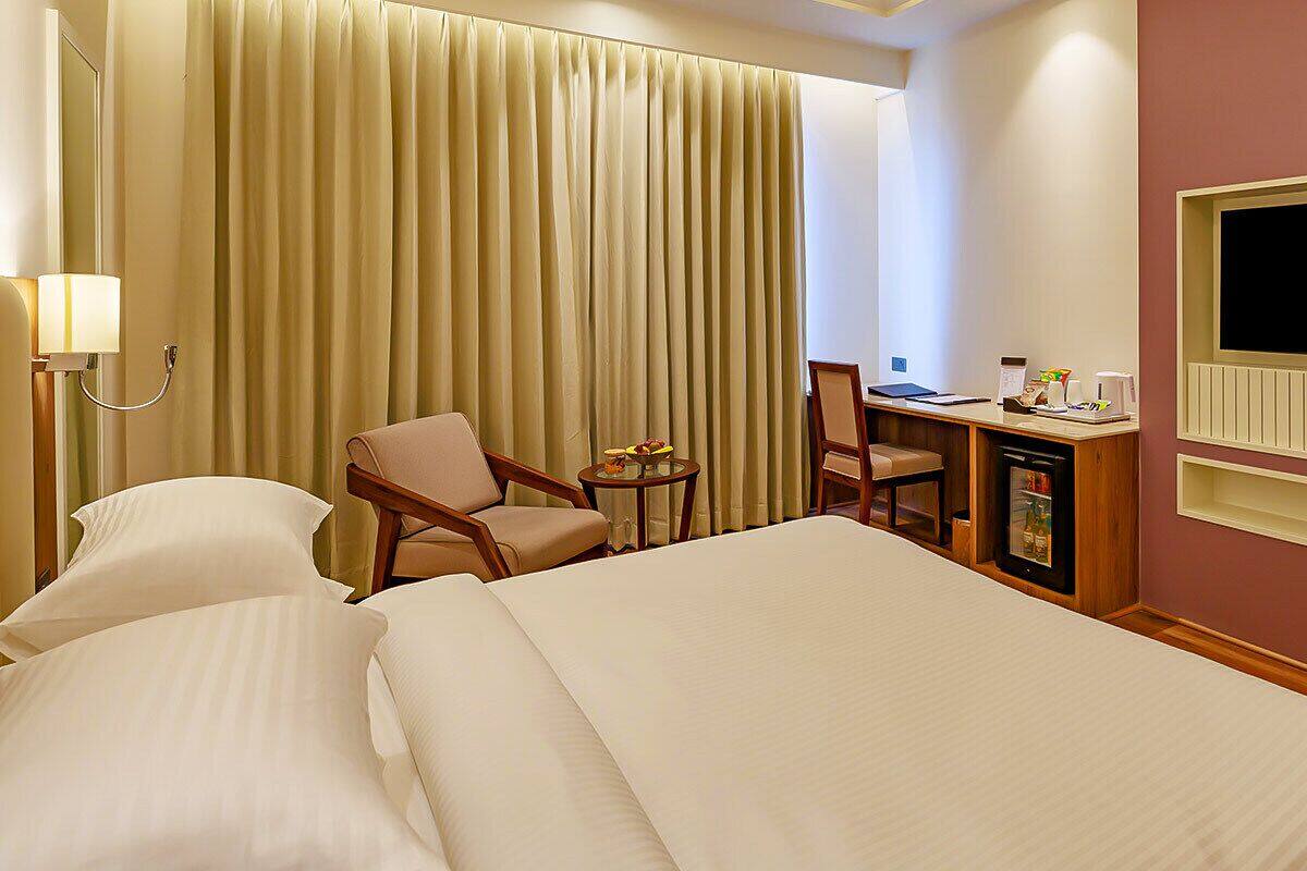 Habitación de hotel con una cama grande, dos sillas, un escritorio, un televisor y un minibar.