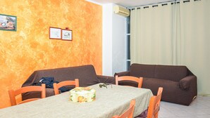 A dining area with a table set for two, two brown sofas, and a window with curtains. - 2 bedroom beautiful apartment in Pozzallo (Pozzallo)
