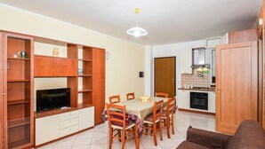 A compact living space with a dining area, kitchenette, and a TV on a wooden cabinet. - 2 bedroom beautiful apartment in Pozzallo (Pozzallo)