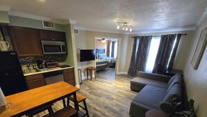 Un espacio habitable compacto con kitchenette, comedor, sofá y televisor.