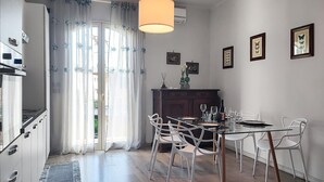 A modern kitchen with a built-in oven, a dining area with a glass table and white chairs, and a large window with sheer curtains. - 2 bedroom gorgeous apartment in Trappitello (Trappitello)