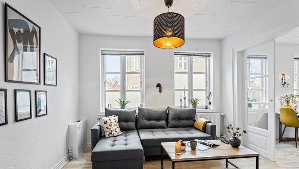 A modern living room with a grey sectional sofa, a coffee table, and a pendant light.