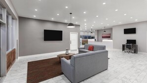 A modern living room with a grey sofa, a coffee table, and a TV mounted on the wall.