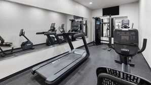 A modern gym with treadmills, elliptical machines, and weightlifting equipment.