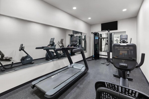 Un gimnasio moderno con cintas de correr, elípticas y equipo de levantamiento de pesas.