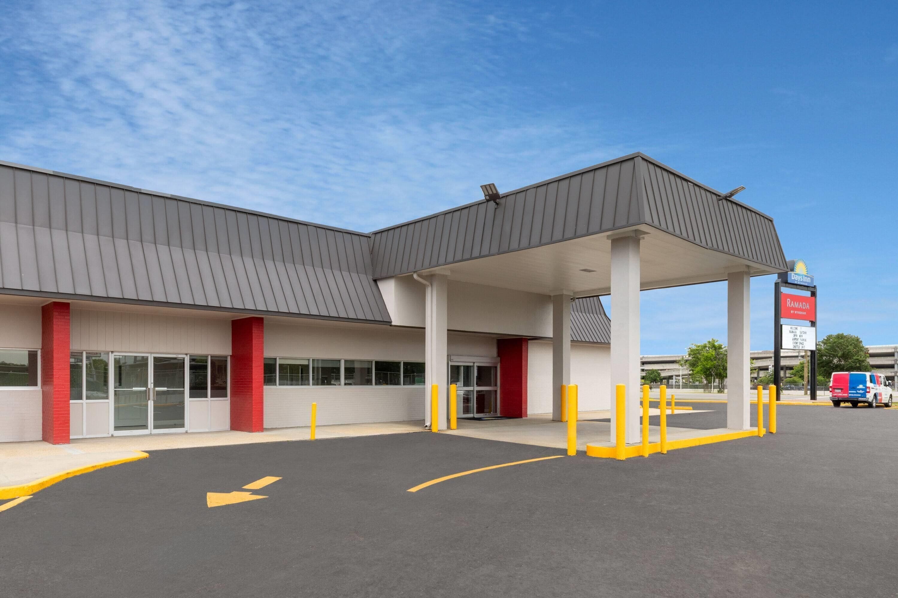 A gas station with a covered fuel pump area, a red and white building, and a clear sky.