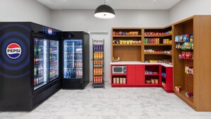 A snack and beverage vending area with Pepsi and mini fridge machines, a microwave, and shelves stocked with snacks and drinks.