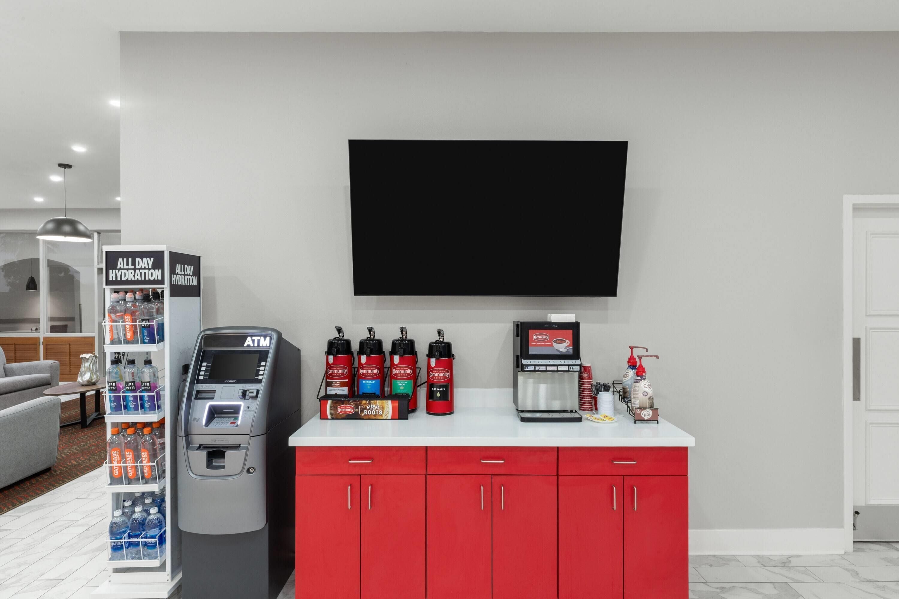 Habitación de hotel con minibar, televisión de pantalla plana, cafetera y dispensador de agua.