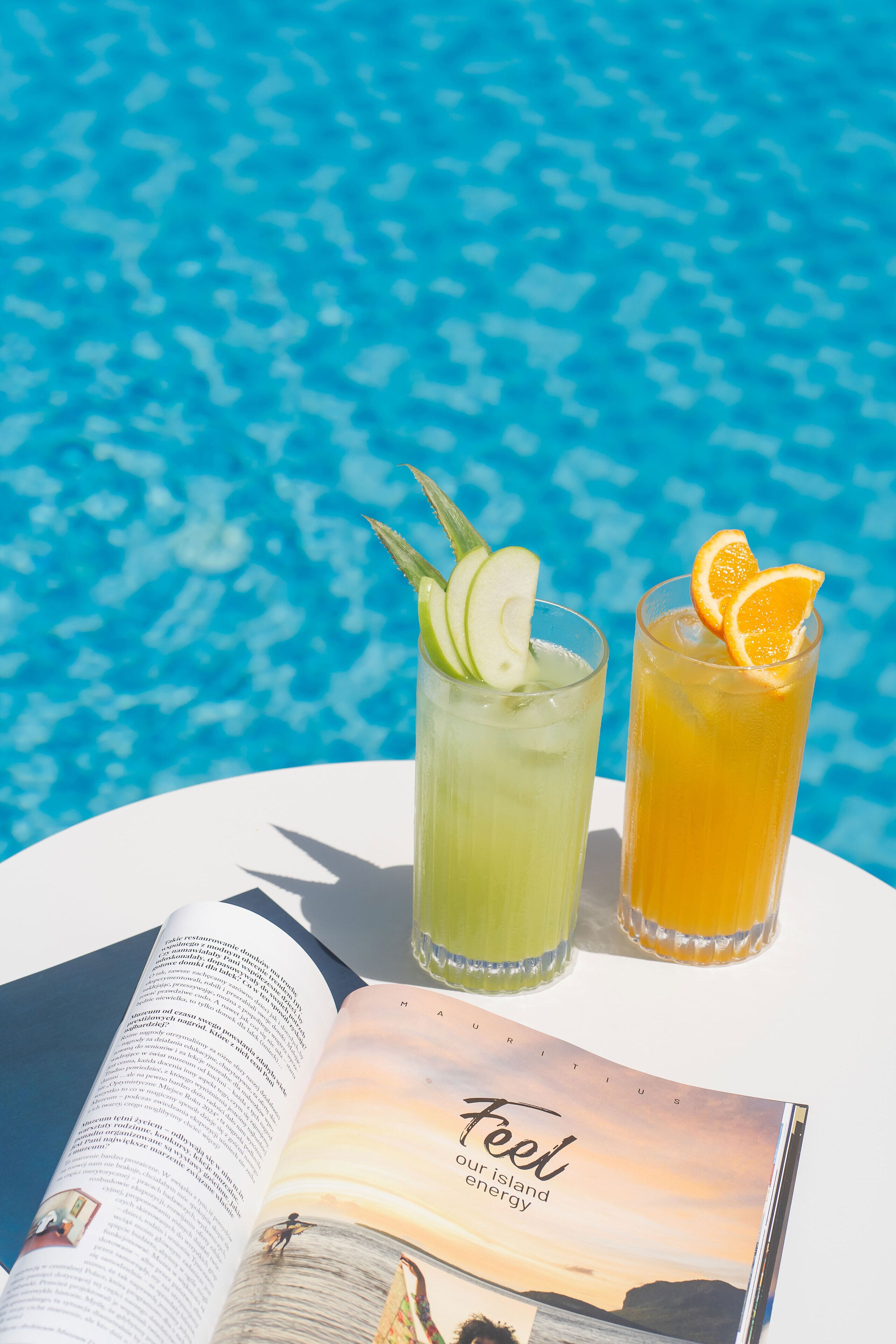 A magazine with the title 'Feel our island energy' and two drinks on a table by a pool.