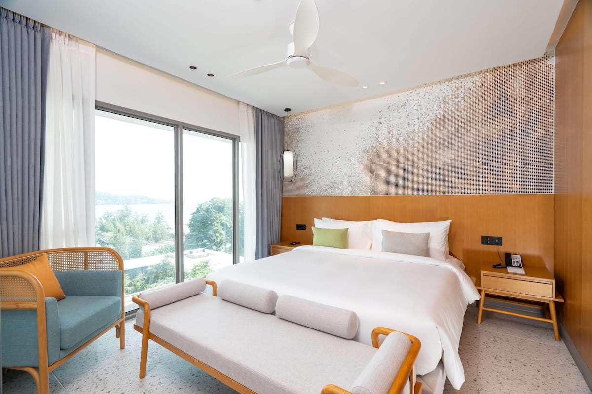 Une chambre d’hôtel moderne dotée d’un grand lit, d’un coin salon et offrant une vue sur l’extérieur.