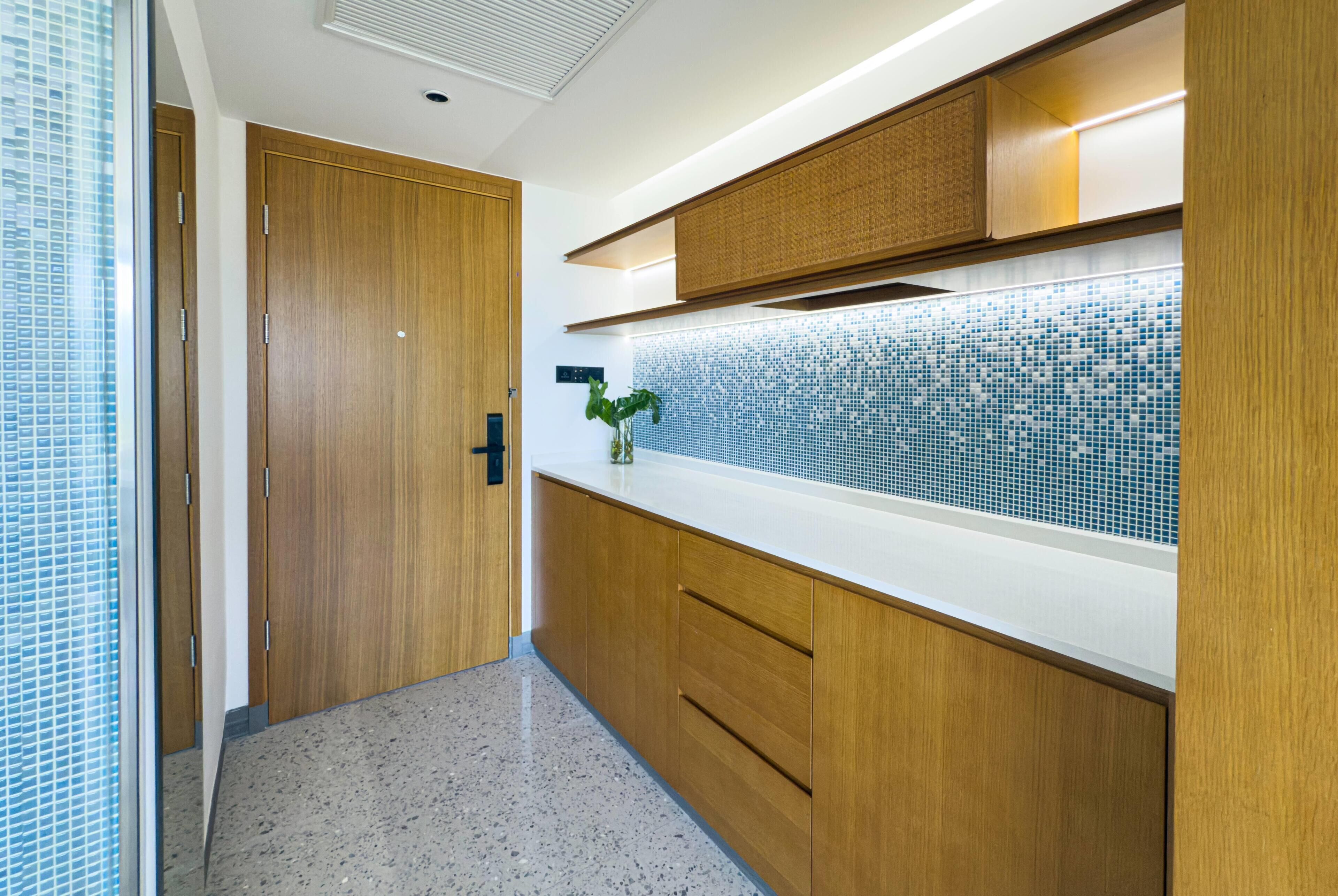 A modern kitchen with wooden cabinets, a tiled backsplash, and a plant on the counter.