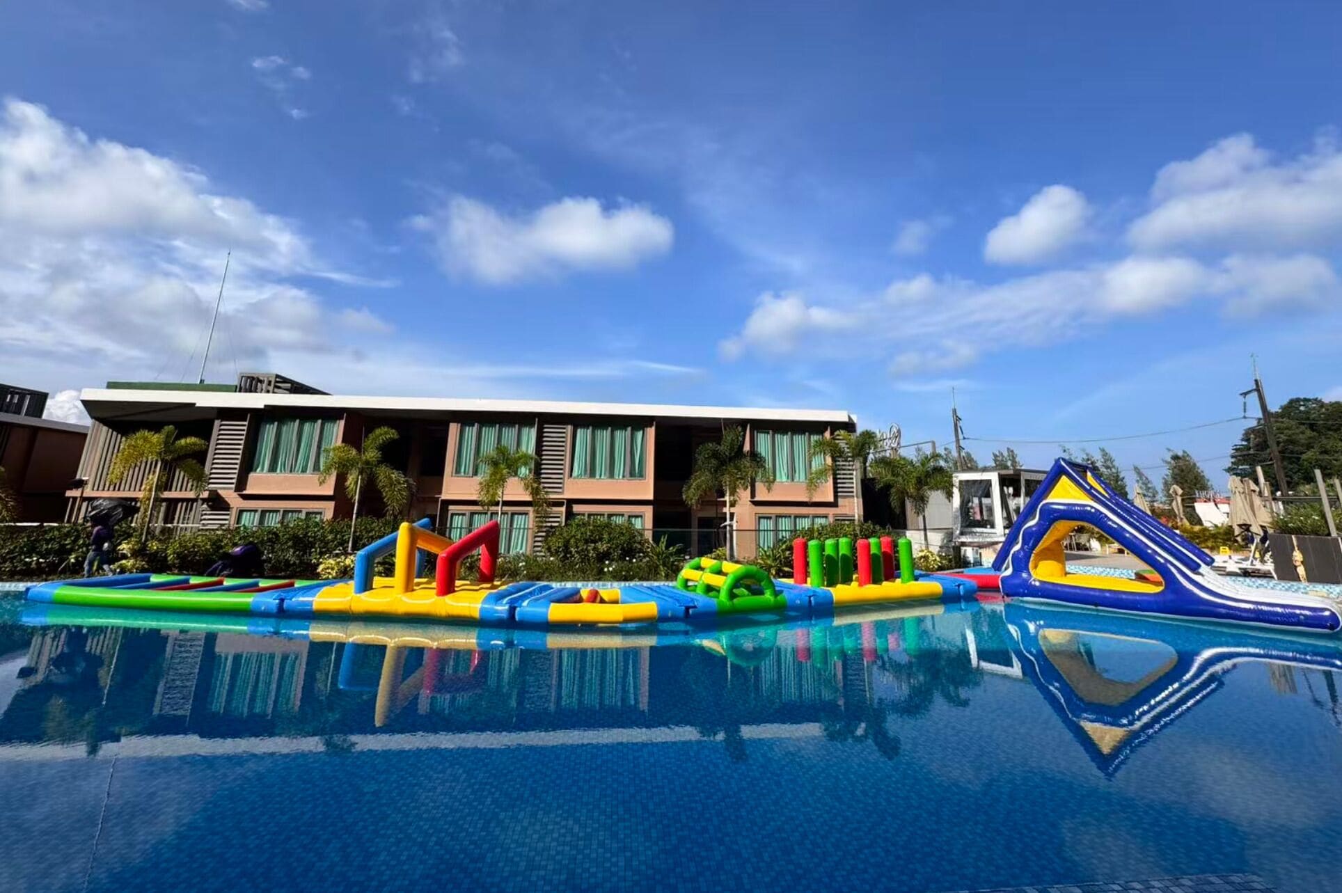 A swimming pool with inflatable play structures and a hotel building in the background.