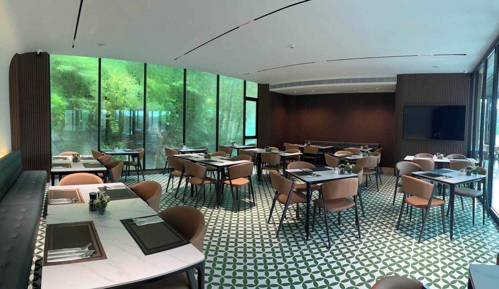 A modern dining area with large windows, a patterned floor, and a mix of table and booth seating.