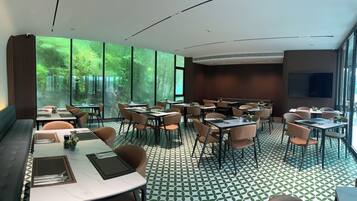 A modern dining area with large windows, a patterned floor, and a mix of table and booth seating.