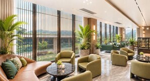 A spacious lounge area with seating, a coffee table, and large windows offering a view of greenery and mountains. - Wyndham Garden Phuket Kamala (Kamala)