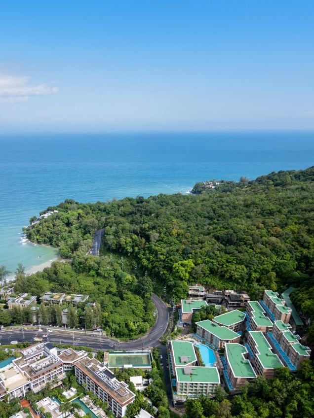 An aerial view of a coastal resort with multiple buildings, roads, and a beach.