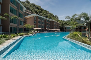 A hotel with a swimming pool, sun loungers, and a view of a forested hill. - Wyndham Garden Phuket Kamala (Kamala)