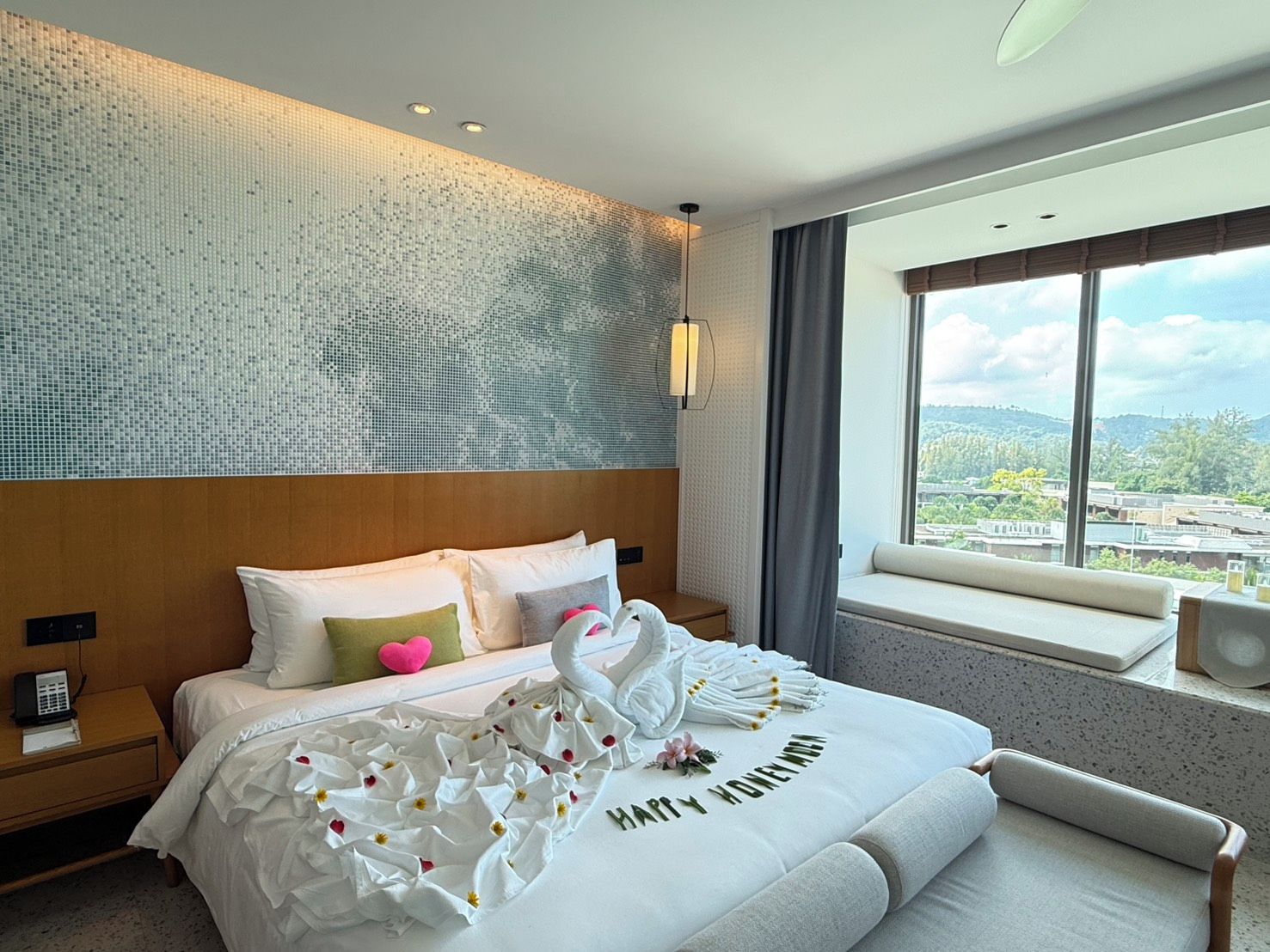 A hotel room with a large bed, a view of the city, and a decorative swan on the bed.