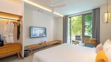A hotel room with a bed, a TV, a desk, a bench, a chair, and a view of the outdoors.