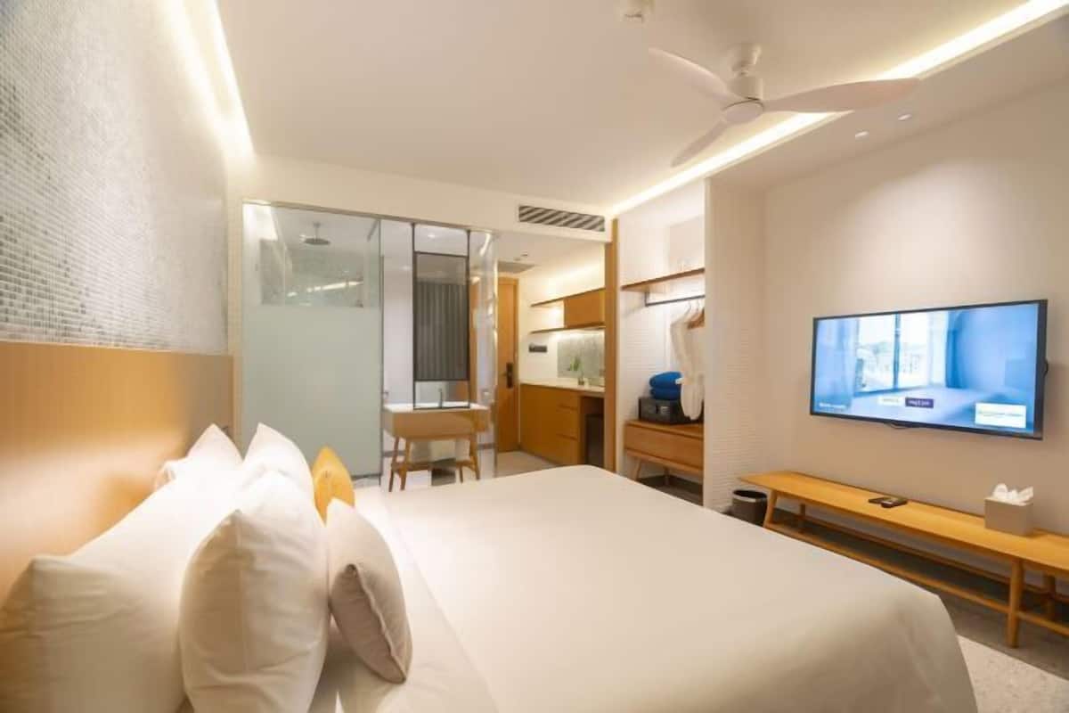Une chambre d’hôtel moderne dotée d’un grand lit, d’un bureau, d’une télévision et d’une porte coulissante donnant accès à la salle de bain.