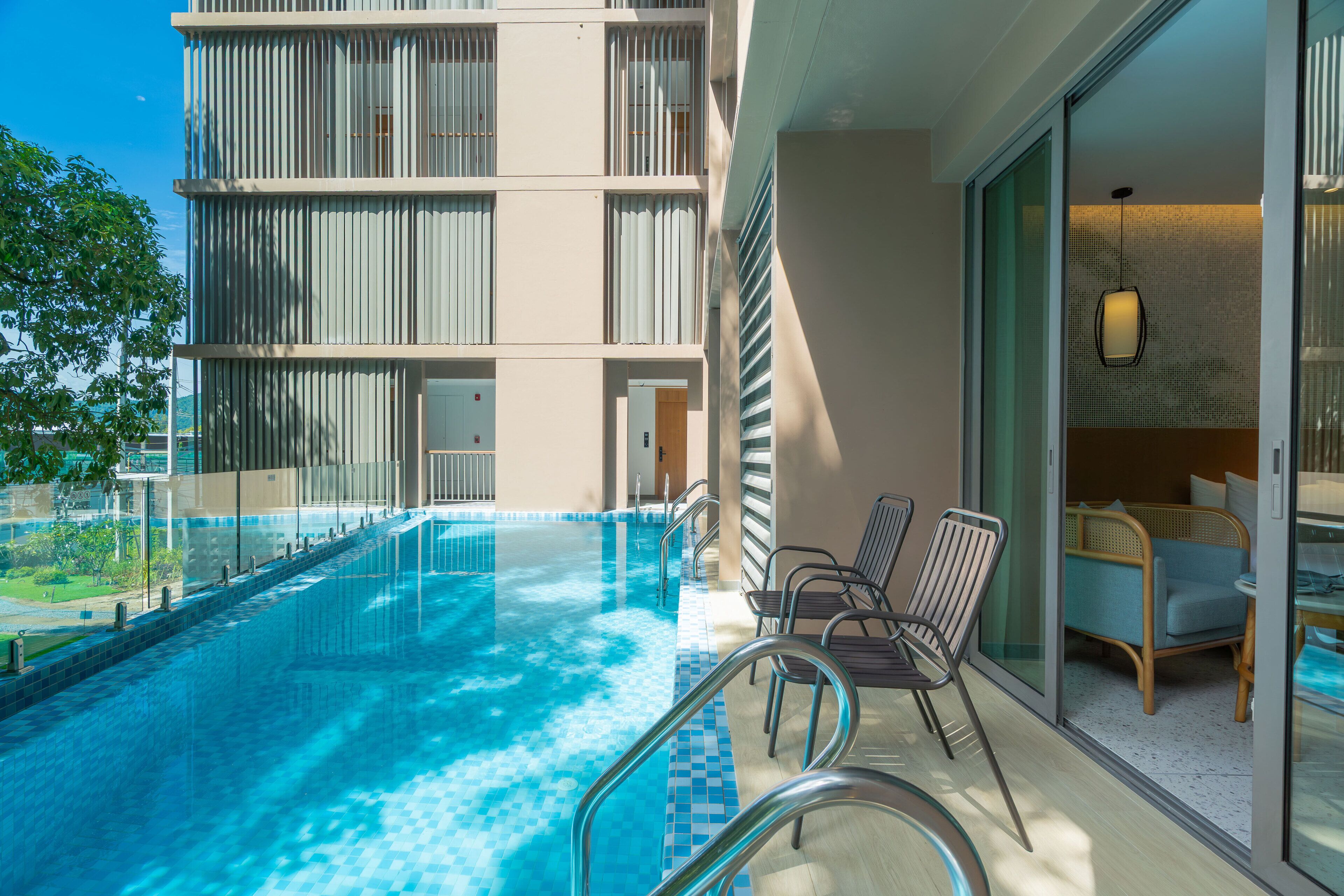 Un hotel moderno con piscina, mobiliario exterior y vistas del exterior del edificio.