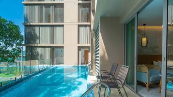 Un hotel moderno con piscina, mobiliario exterior y vistas del exterior del edificio.