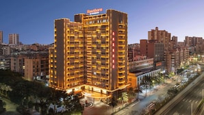 A multi-story hotel with a prominent sign at the top, surrounded by other buildings and a busy street.