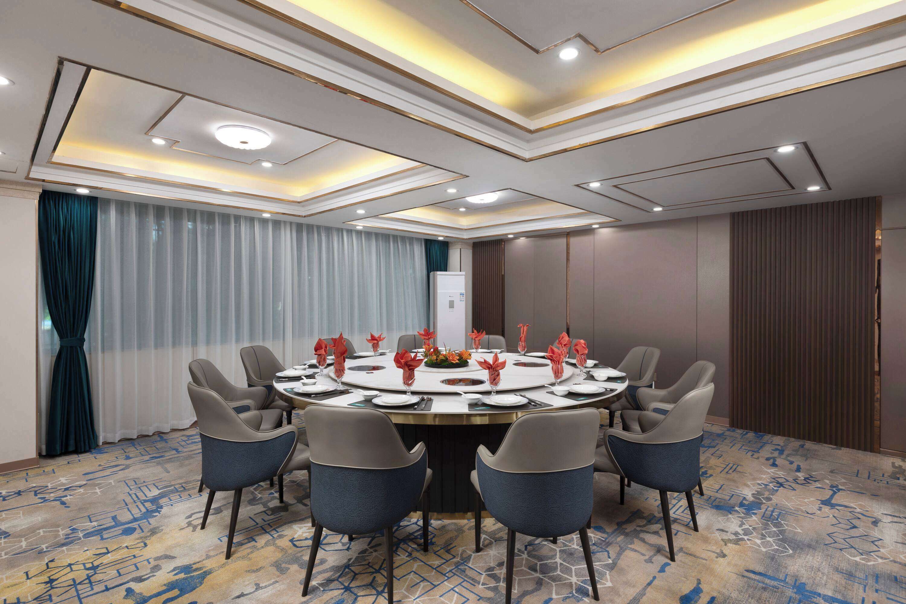 A conference room with a round table, six chairs, and a modern ceiling design.