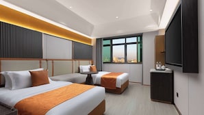 A hotel room with two beds, a small table, a TV, and a city view.