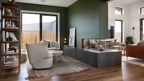 A modern living room with a fireplace, a bookshelf, and a large window. - Ridge Vue Retreat - the ultimate in style and serenity (Daylesford)